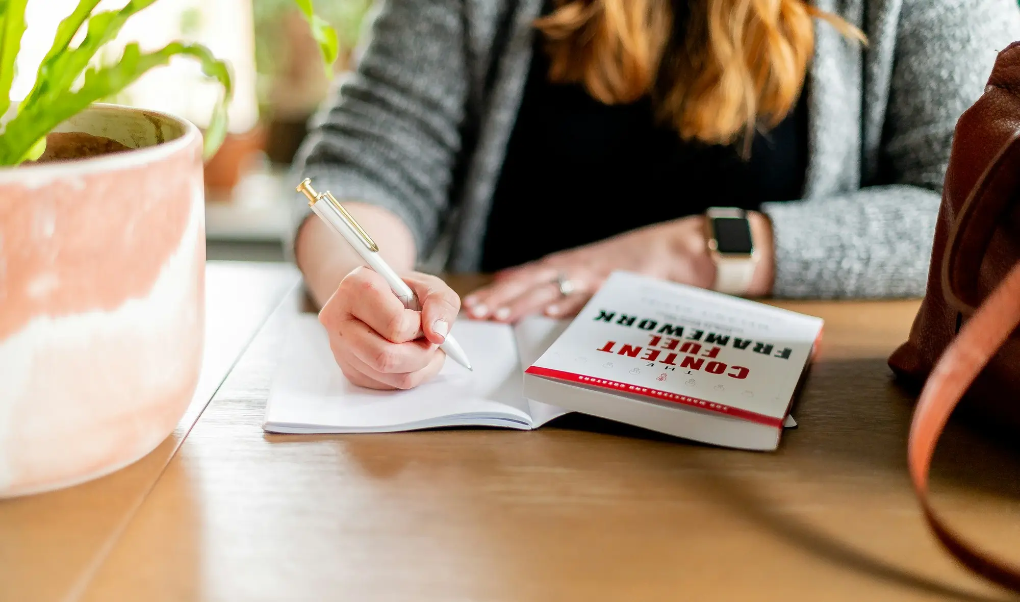 Business owner handwriting notes for a letter of explanation at a cafe table