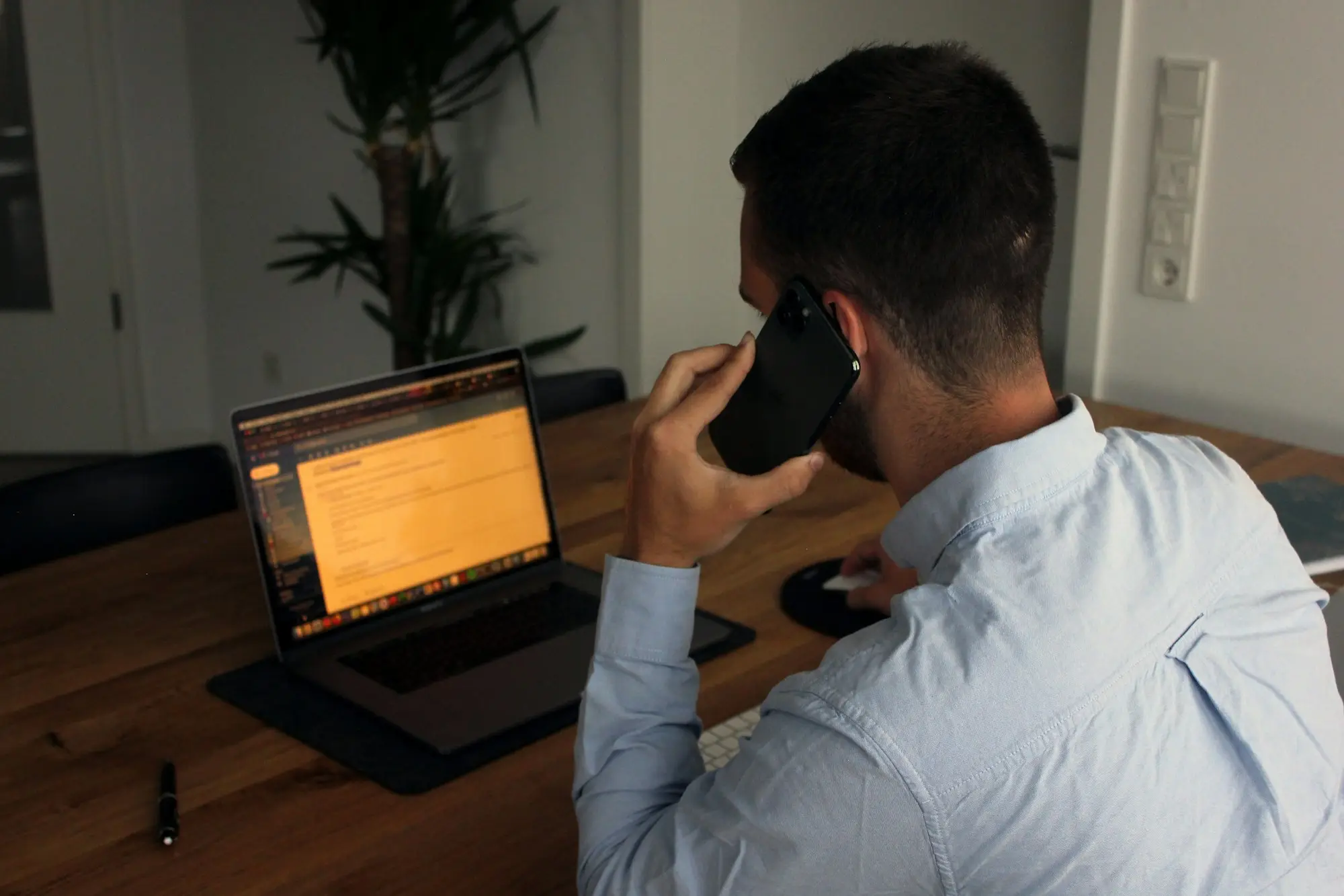 Finance specialist on a phone call with a client, taking notes at a bright office desk